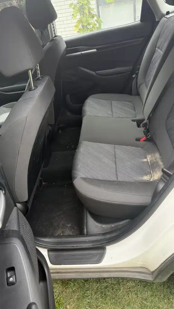 Kia rear seat upholstery with visible staining before interior cleaning.