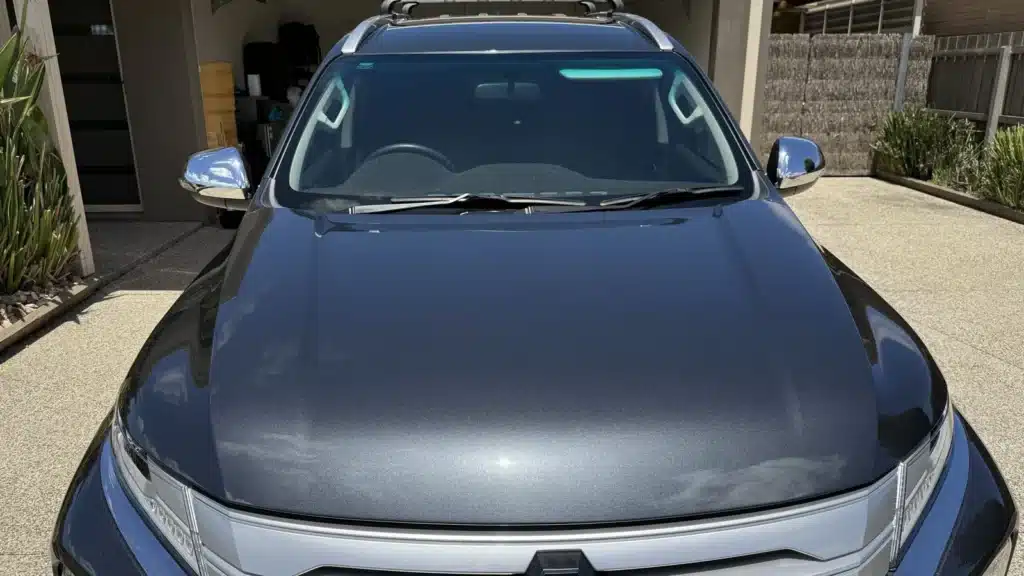 Glossy bonnet of a Mitsubishi Pajero after paint correction on a residential driveway.